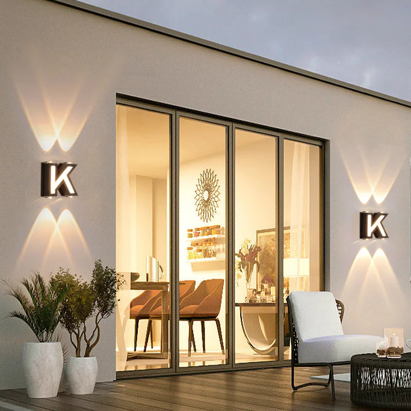 Udendørs væglampe med LED-belysning og personligt bogstav – set udefra om aftenen