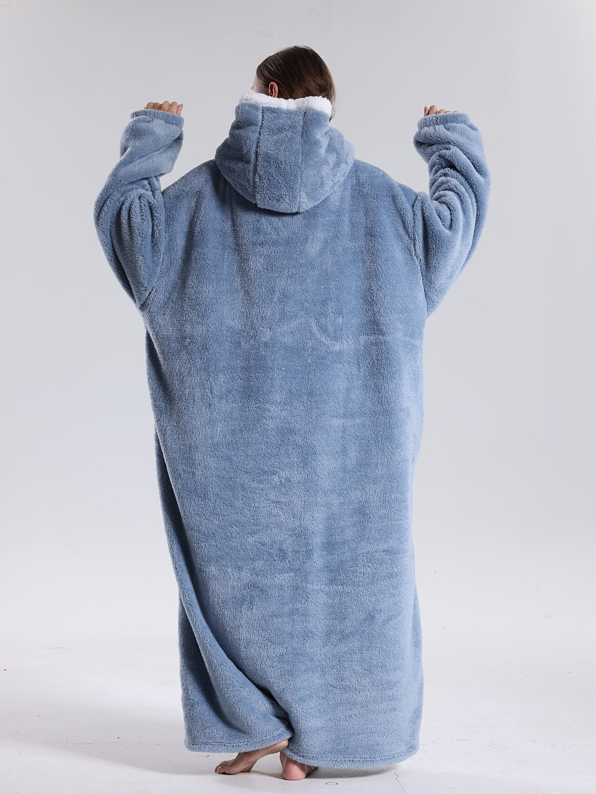 Person iført oversized hoodie-tæppe på sofa